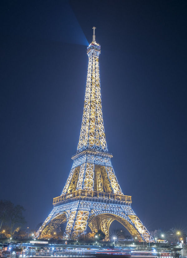 Eiffel Tower covered in twinkling lights during the evening.