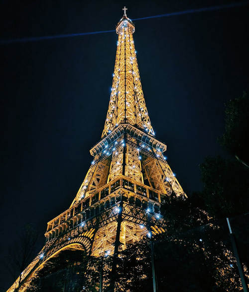 Eiffel Tower illuminated at night against a dark sky